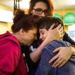 Eleven-year-old Quinn Schmitz shares a moment with her mom, Sarah Blakeley, and her grandmother, Anita Kerwood, at ATI Physical Therapy on Thursday in Everett. The ATI Foundation surprised Schmitz with a new tricycle in front of her family, friends and physical therapists. (Daniella Beccaria / The Herald)