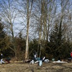 Volunteers stack garbage at the edge of a former homeless encampment near Monroe on Saturday, Feb. 25. (Ian Terry / The Herald)