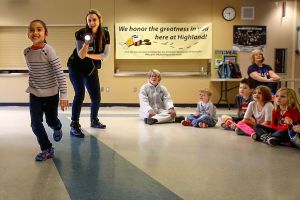 In a game demonstrating the speed of light in front of all her K thu 2 classmates, Highland Elementary first-grader, Ava Aguero tries her hardest to outrun light from a flashlight held by Janice Crew of the Pacific Science Center during a &ldquo;space&rdquo; presentation Thursday at the school. (Dan Bates / The Herald)