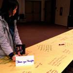 An Edmonds Community College student writes her reactions to the college&rsquo;s &ldquo;Tunnel of Intersections&rdquo; exhibit Wednesday in Woodway Hall on campus. The exhibit highlights experiences and challenges of diverse groups. (Julie Muhlstein / The Herald)