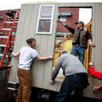Snohomish High School students Grant Olson (center left) and Bryan Slavin (top) work alongside other students and faculty on Saturday to install a wall on a tiny house being built for a multi-school construction competition. After the contest, the structures will be donated for use as transitional shelters for homeless people in Seattle. (Ian Terry / The Herald)