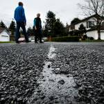 Allen and Bundie Olsen walk near a broken patch of chip seal on Tuesday close to their home in the Wildflower neighborhood of Mill Creek. The rough surface was layed in July and August of 2016 and has since caused problems for residents like the Olsens whose yard and driveway are constantly filled with rocks from the street. (Ian Terry / The Herald)
