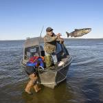 Chip Fields tosses a freshly caught salmon to shore while his son Devin, 10, leans over to haul another fish out as they catch fish to prepare for the upcoming winter.