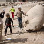A child poses for a picture with part of a recently discovered statue in a Cairo slum Friday. (AP Photo/Amr Nabil)