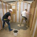 While spreading skim coat, Arlington High sophomore Anthony Whitis almost gets himself stuck in a corner as Caden Smith watches while they work on a tiny home. (Andy Bronson / The Herald)