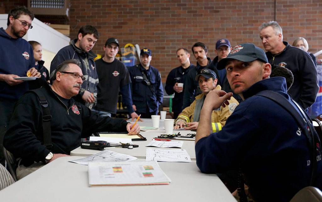 Oso fire Lt. Tim Harper, front right, and other first responders gather inside the fire station on March 22, 2014, in the hours after the mudslide. Harper, now a captain with the department, has help distribute over $500,000 in financial aid to victims and their families. (Annie Mulligan / The Herald)