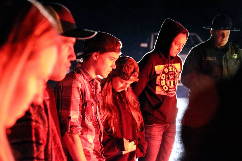 Participants bow their heads in prayer at the scene of the disaster. (Kevin Clark / The Herald)
