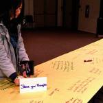 An Edmonds Community College student writes her reactions to the college&rsquo;s Tunnel of Intersections exhibit Wednesday in Woodway Hall on campus. The exhibit highlights experiences and challenges of diverse groups. (Julie Muhlstein / The Herald)