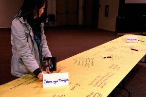 An Edmonds Community College student writes her reactions to the college&rsquo;s Tunnel of Intersections exhibit Wednesday in Woodway Hall on campus. The exhibit highlights experiences and challenges of diverse groups. (Julie Muhlstein / The Herald)