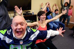 Larry Berg (nearest) enthusiastically helps Willow Place actifvity manager Rachel Hawkins (center) lead a modified yoga class early Tuesday at Quilceda Community Services in Marysville. (Dan Bates / The Herald)