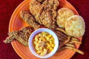 A carryout from Popeyes Louisiana Kitchen displayed on a plate at home has New Orleans style chicken, buttermilk biscuits, Cajun fries and macaroni and cheese. (Andrea Brown/The Herald)