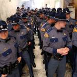 New Washington State Patrol troopers stand huddled in a hallway before the Washington State Patrol Academy graduation ceremonies in the Capitol rotunda, Wednesday in Olympia. The 49 graduates of the 107th Trooper Basic Training Class went through nearly six months of field and academy training, and were given the oath of office by Washington State Supreme Court Justice Mary Fairhurst. (AP Photo/Elaine Thompson)