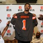 Myles Garrett holds up a Cleveland Browns jersey Thursday as his mother, Audrey Garrett (left) cheers with Bruce Smith (right) at Terre Verde Golf Course in Arlington, Texas. (Nathan Hunsinger/The Dallas Morning News via AP)
