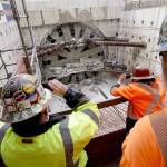 Workers watch and take photos as a massive tunneling machine finishes breaking through a five-foot-think concrete wall to complete boring for the Highway 99 tunnel under Seattle on Tuesday. (AP Photo/Elaine Thompson)