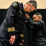 Tyson Webster, 9, of Shoreline, pins a badge on Lynnwood&rsquo;s new Chief of Police Tom Davis on Tuesday, April 25, at the Lynnwood Convention Center. (Dan Bates / The Herald)