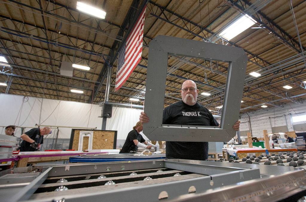 Electric Mirror employee Thomas Kelly stacks a mirror frame Monday, April 24, in Everett. Kelly is one of 385 employees at the Everett plant. (Andy Bronson / The Herald)