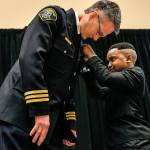 Tyson Webster, 9, of Shoreline, has the honor of pinning the badge on Lynnwood&rsquo;s new chief of police, Tom Davis, on Tuesday during a celebration at the Lynnwood Convention Center. (Dan Bates / The Herald)