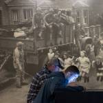 A mural shows soldiers watching children jumping rope as Hunter Thompson, 17, front, listens to war stories next to his father, Jason, in the Flying Heritage & Combat Armor Museum&rsquo;s new exhibit, &ldquo;Why War?&rdquo; on Thursday in Everett. (Andy Bronson / The Herald)