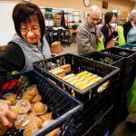 Volunteer Rosalinda Taculad (left), of Marysville, scoops up a handful of fruit containers to be packed into food bags for local schools with kids in need at the Marysville Community Food Bank on April 27. Funding for some of the food bank&rsquo;s programs comes from Community Development Block Grants which the Trump administration proposes to eliminate. (Ian Terry / The Herald)