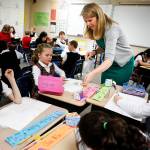 Second grade teacher Stephanie Hill helps students with an Easter assignment. (Ian Terry / The Herald)
