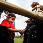 Belle Mahoney, 6, laughs as fresh water runs through her hands from a faucet opened Friday at the Tulalip Reservation during a ceremony to celebrate a newly opened water line that will provide clean drinking water to Tulalip. (Ian Terry / The Herald)