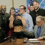Gov. Jay Inslee talks with supporters of theatrical wrestling Monday in Olympia before signing a bill that creates a license for theatrical wrestling schools. Under the measure, any licensed theatrical wrestling school would be allowed to schedule a certain number of public performances. (AP Photo/Rachel La Corte)