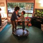 Ian Fisher watches a game as his mother, Deanna Fisher, plays with her youngest son, 4-year-old Colin, who lives with autism, at their home in Bothell. The Fishers plan to donate baby teeth from their youngest sons for a national study that will try to determine if prenatal and early-life exposure to chemicals increases a child&rsquo;s chances of developing autism. (Kevin Clark / The Herald)