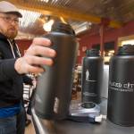 Owner Bryan Miller grabs growlers for a display as he, co-owner Don Webb and staff work to get Naked City Brewery ready for its soft opening on April 20 on Camano Island. (Andy Bronson / The Herald)