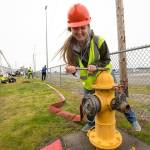 Natalie Giard leans hard as she opens a fire hydrant as she and other teens learn what it take to be a firefighter at the Trade UP event at Arlington Airport on Tuesday. (Andy Bronson / The Herald)