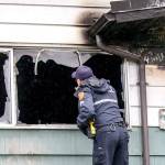 An Everett police officer examines the remains of a house fire Saturday morning in Everett. (Kevin Clark / The Herald)