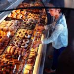 Melissa Despi restocks displays, including those containing some of their American-style doughnuts, at the customer service counter. (Dan Bates / The Herald)