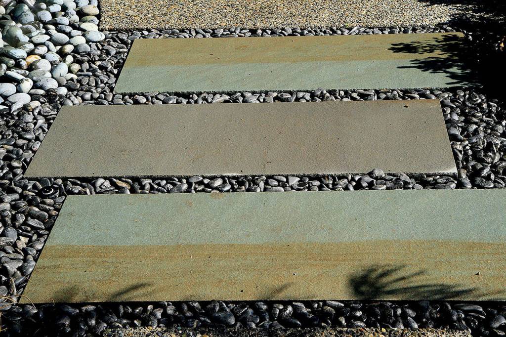 A path made of concrete slabs with black beach pebbles lead to a patio. (Pam Roy photo)