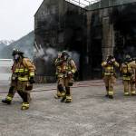 Firefighters make their way out of a building used for a fire simulation at the Washington State Fire Training Academy near North Bend on Tuesday. (Ian Terry / The Herald)