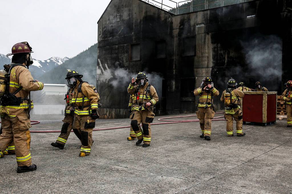 Firefighters make their way out of a building used for a fire simulation at the Washington State Fire Training Academy near North Bend on Tuesday. (Ian Terry / The Herald)