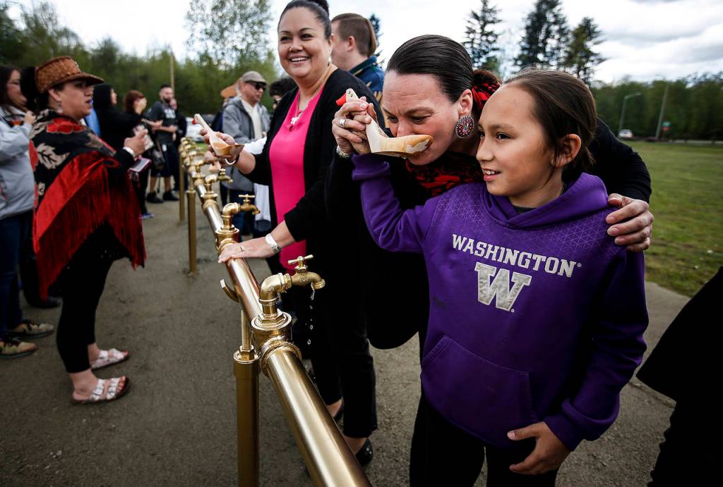 Theresa Sheldon takes a sip of water from a handcarved spoon with the help of her 11-year old, Klayton. (Ian Terry / The Herald)