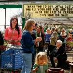 A sign near the back of one of three long lines to check out stands at Wight&rsquo;s Home & Garden sale, Friday, carries a message of thanks to longtime customers&mdash;with an unusual sign-off. Customers nearest are Judy Hobert (far left) Oksana Donskoy (pink) Martha Overland and her grandaughter Isabelle Strandy, 2, and Ellie Norsworthy-Tingley (sitting). (Dan Bates / The Herald)