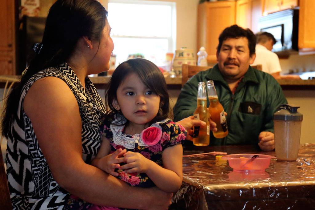 Justina Hernandez-Antonio, holding Maritza Martinez-Hernandez, toasts with her husband Eutiquio Martinez-Garcia in their dining room.                                (Kevin Clark / The Herald)