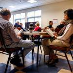 Husband and wife Hemant (left) and Mamta Shah read while waiting to enter a duplicate bridge game by way of rotation, due in part to the lower numbers of players available and needing an even four players per table. (Dan Bates / The Herald)