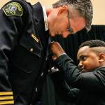 Tyson Webster, 9, of Shoreline, has the honor of pinning the badge on Lynnwood&rsquo;s new chief of police, Tom Davis, on Tuesday during a celebration at the Lynnwood Convention Center. (Dan Bates / The Herald)