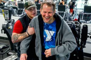 Firmly in the grip of his assistant, Kacey Walker, Stanwood&rsquo;s Todd Duitsman, who has been paralyzed since a 2014 body surfing accident on Maui, stands up from his wheelchair and attempts a step forward Wednesday at the Marysville YMCA. (Dan Bates / The Herald)