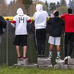 Snohomish junior Bohdi Uderitz (left) leaps up and down to see over the outfield wall as spectators watch a softball game between Snohomish and Meadowdale on April 25 in Snohomish. (Andy Bronson / The Herald)