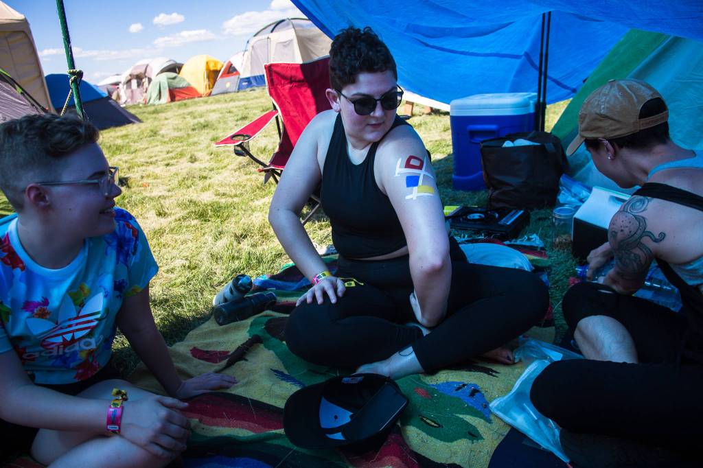 Oak Sonfist (center) admires her body paint while hanging out with her friends Olivia Caron-Noble (left) and Haley Irving (right) on the first of three days during the annual Sasquatch! Music Festival on Friday, May 26, 2017 in George, Wa. (Daniella Beccaria / For the Herald )
