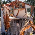 Brent Morgan of Absolute Construction Co. watches through a doorway as co-worker Eric Mahlman uses a backhoe and rope to pull a large chunk of ceiling and roof off a house in Lake Stevens. The house, known to some as the &ldquo;spaceship house,&rdquo; was built in 1983 near North Lakeshore Drive and Main Street. Long before the demolition was begun Monday, the house had fallen into disrepair and the owner finally decided to tear it down. (Dan Bates / The Herald)