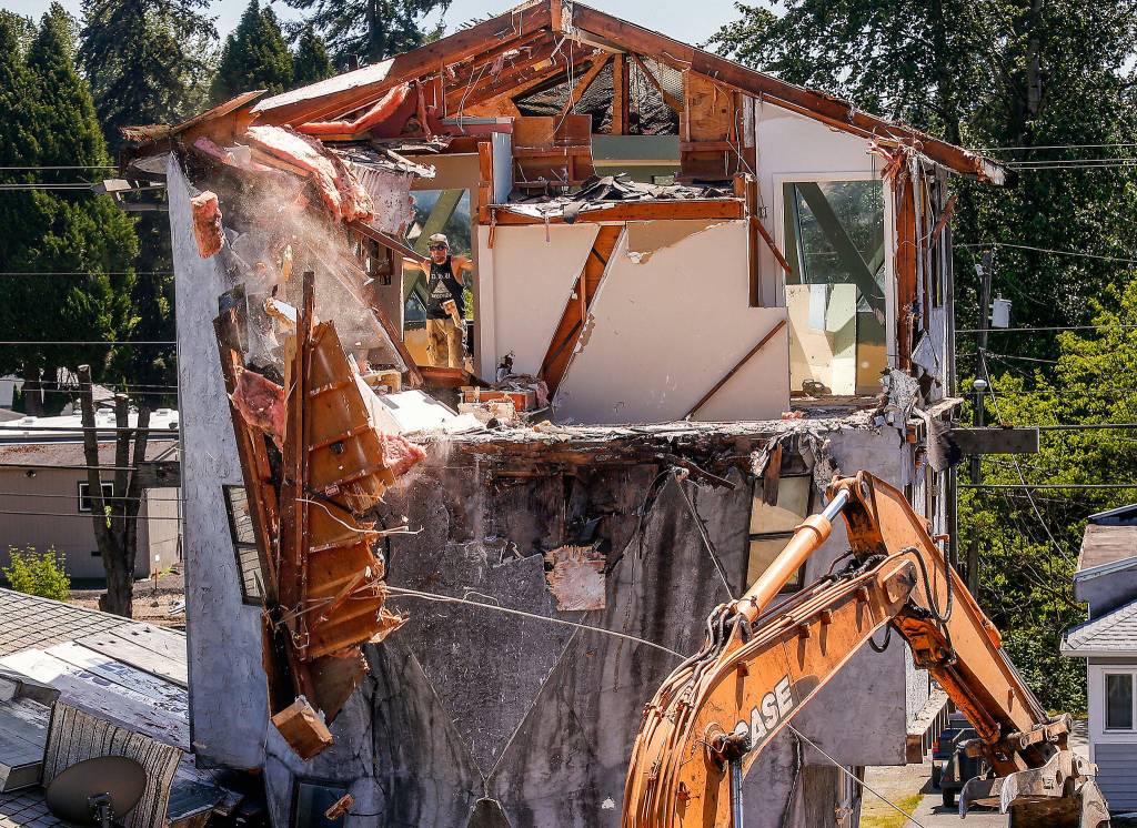 Brent Morgan of Absolute Construction Co. watches through a doorway as co-worker Eric Mahlman uses a backhoe and rope to pull a large chunk of ceiling and roof off a house in Lake Stevens. The house, known to some as the &ldquo;spaceship house,&rdquo; was built in 1983 near North Lakeshore Drive and Main Street. Long before the demolition was begun Monday, the house had fallen into disrepair and the owner finally decided to tear it down. (Dan Bates / The Herald)
