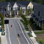 A pedestrian and bicyclist cross Riverfront Boulevard, a road to leading to new homes, on Wednesday in Everett. Everett is among the top 10 places experiencing the most growth in the state. (Andy Bronson / The Herald)