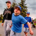 Brothers Matthew Irish, 15 (left), and Noah, 11, follow their older brother, Jacob, 16, as they walk to their car from the baseball field at Lakewood Middle School on Thursday after games were canceled by lightning. Jacob, who was born with life-threatening Hurler syndrome, is playing on a baseball team for the first time. (Dan Bates / The Herald)