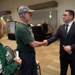 New Silvertips head coach Dennis Williams shakes hands with longtime season ticketholders Doris Rupert and Tom Rupert on Monday at the Edward D. Hansen Conference Center in Everett. (Andy Bronson / The Herald)