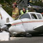 A firefighter and two Snohomosh County Airport workers look over a plane that made an emergency landing May 2 on Harbour Pointe Boulevard SW and Mukilteo Speedway after losing power on takeoff from Paine Field. The pilot walked away unhurt, but a passenger received minor injuries. Several cars were damaged. (Andy Bronson / The Herald)
