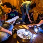 Brian Flansburg (left) looks for clues in a document while his friends try and decode other messages at the new Escape Scene in downtown Everett May 6. (Ian Terry / The Herald)