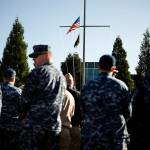 Navy service members stand facing an American flag after it was lowered to half-mast during a ceremony held at Naval Station Everett on Thursday marking Memorial Day. (Ian Terry / The Herald)